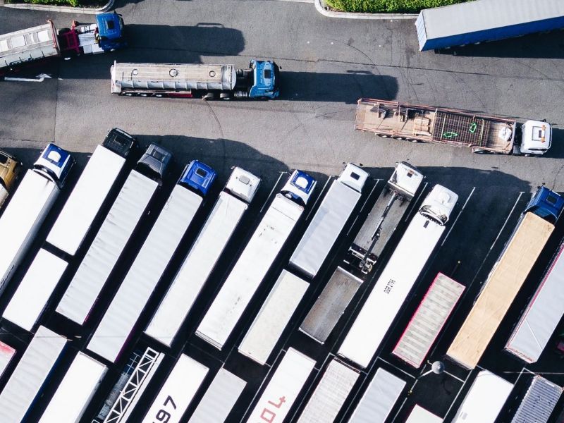 An overhead view of semi trucks arranged in rows in a parking lot.